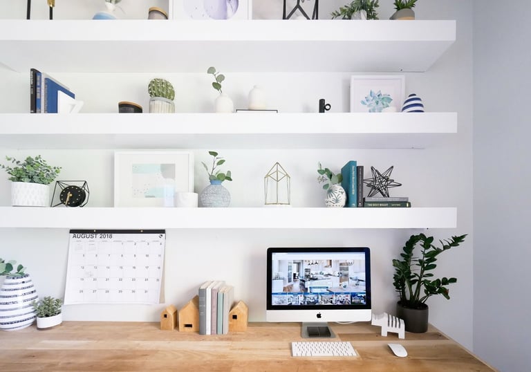 Minimalist home office with wooden desk, floating shelves, plants, and computer