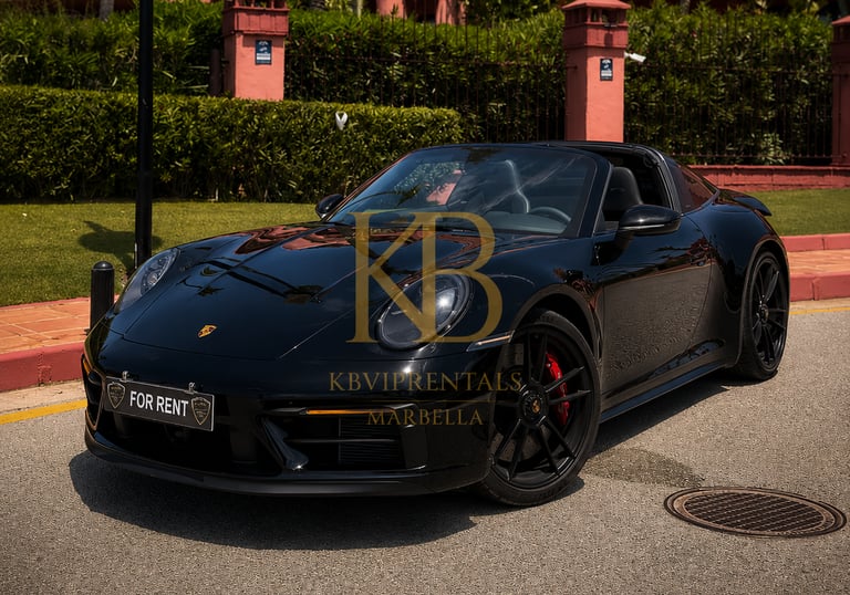 Sleek black Porsche 911 Targa convertible for rent in Marbella, parked on a sunny street in front of a luxury resort.
