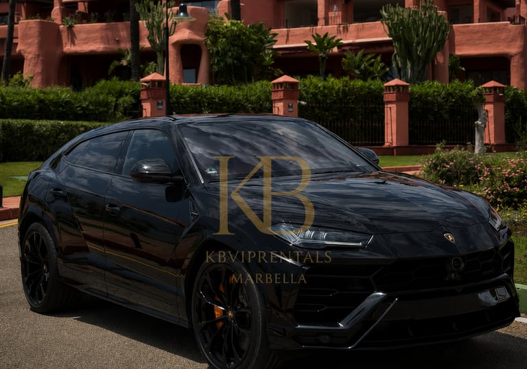 Sleek black Lamborghini Urus SUV parked in front of a luxurious peach-colored building with manicured landscaping, Marbella