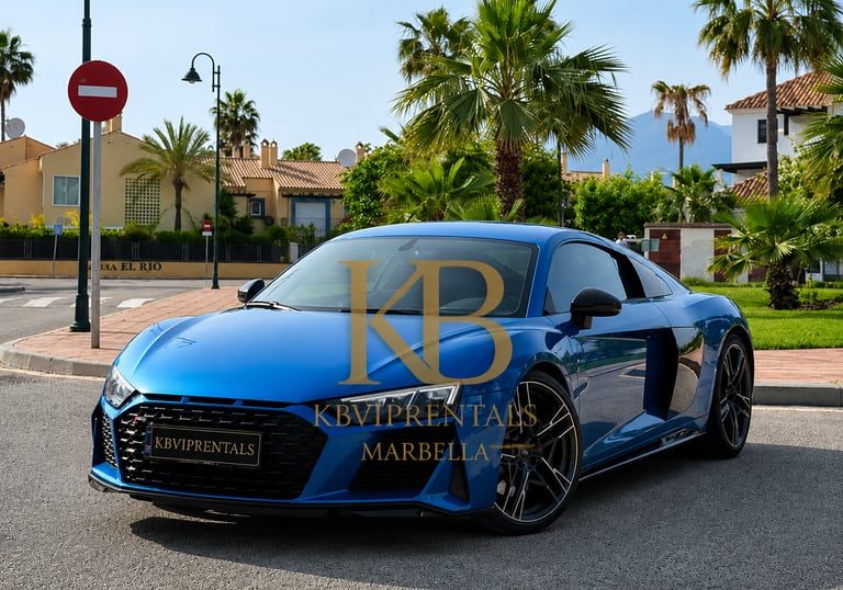 Luxury blue Audi R8 sports car for rent in Marbella, Spain, parked on a sunny street with palm trees.