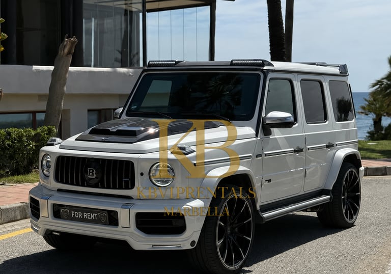 White Brabus G-Wagon luxury SUV rental parked on a sunny road in Marbella with sea views.