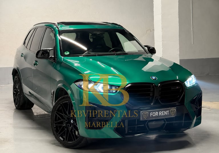 A metallic emerald green BMW X5 M luxury SUV with black rims parked in a garage for rent in Marbella.