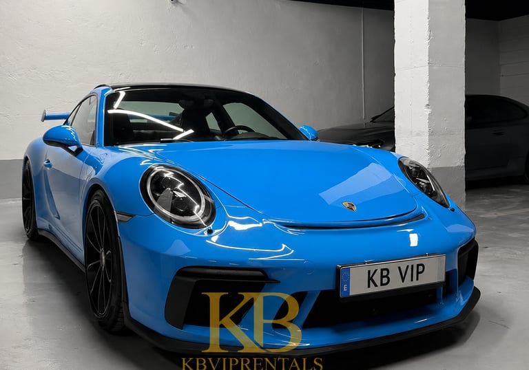A vibrant blue Porsche 911 GT3 luxury sports car parked in a Marbella rental garage.