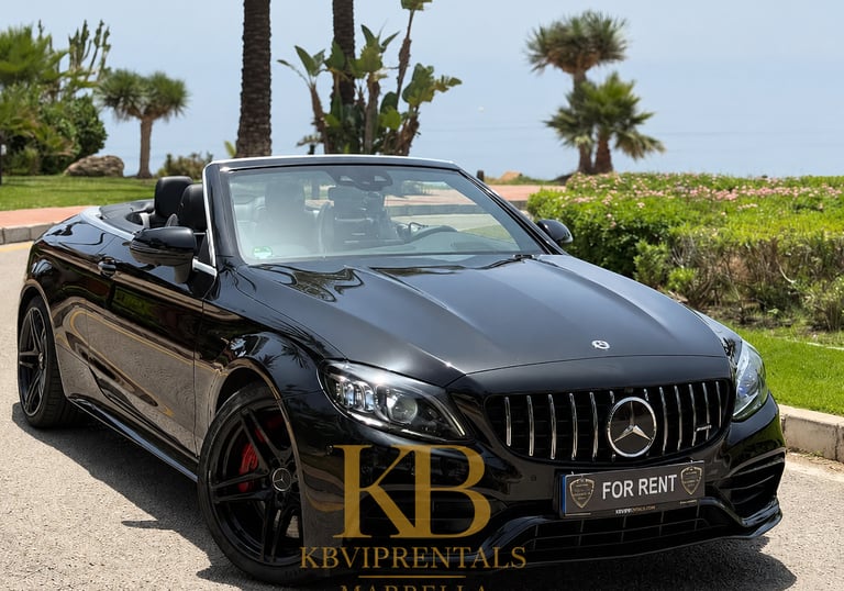 Black Mercedes AMG convertible luxury car rental parked in Marbella near tropical palm trees.