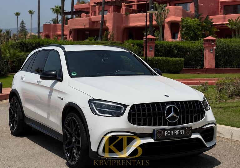White Mercedes-Benz AMG SUV for rent parked in front of a luxury pink Mediterranean villa in Marbella.