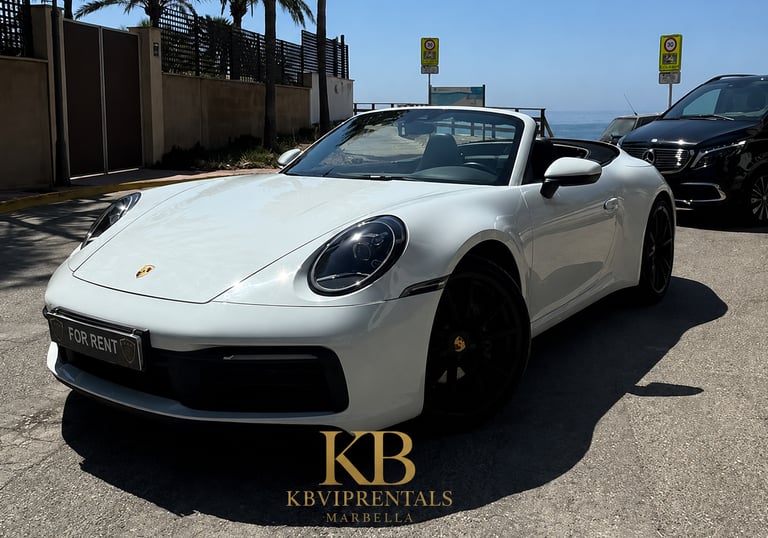 White Porsche 911 Carrera convertible luxury rental car parked on a sunny street in Marbella.