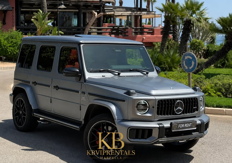 Matte grey Mercedes-Benz G-Class luxury SUV for rent parked in a sunny tropical location.