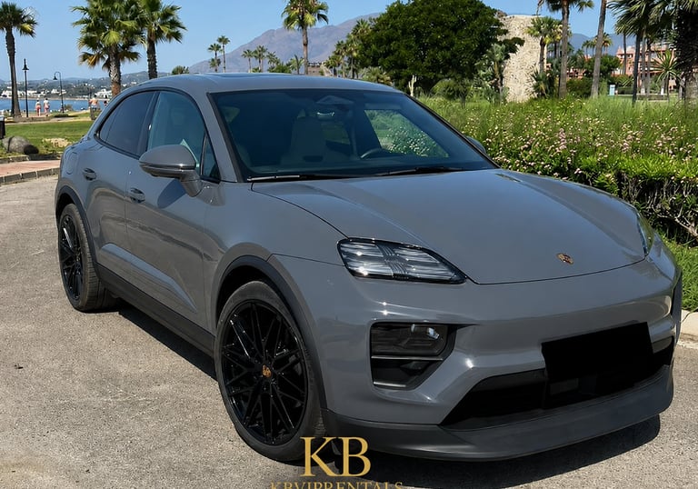 Luxury grey Porsche Macan electric SUV parked in Marbella with palm trees and mountains.