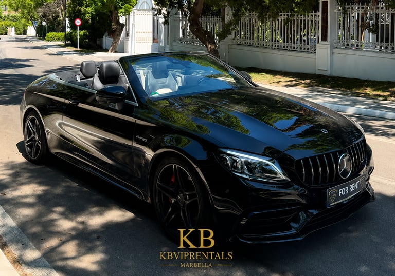 Black Mercedes AMG convertible luxury car rental parked on a sunny street in Marbella.