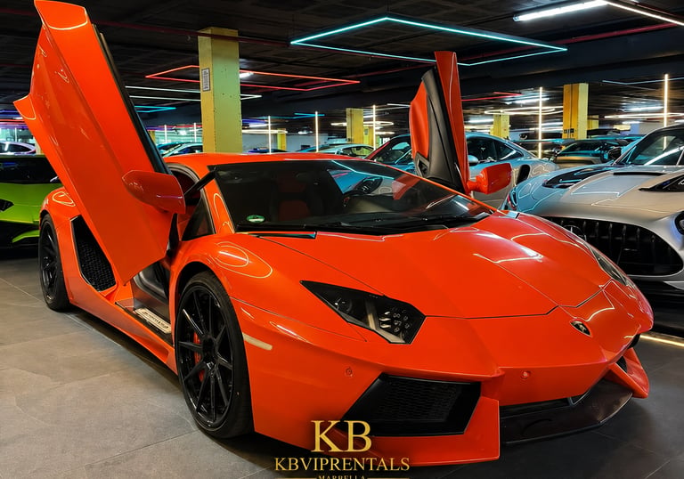 Bright orange Lamborghini Aventador with scissor doors open in a luxury car showroom.