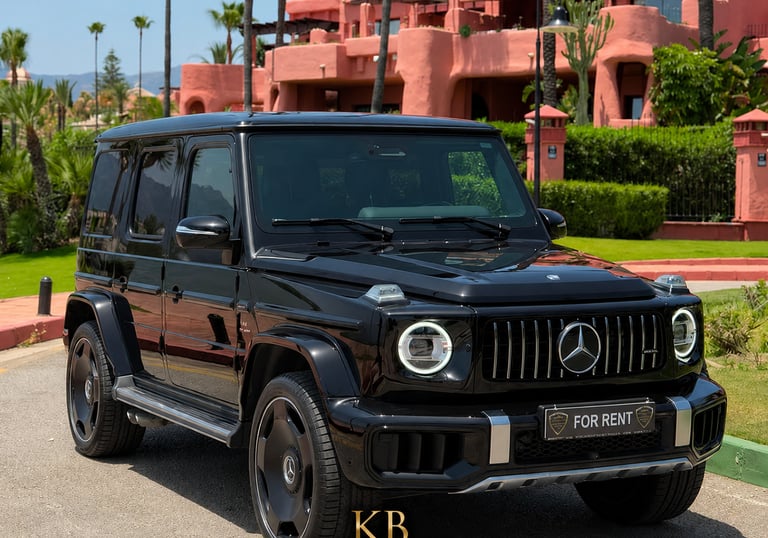 Black Mercedes-Benz G-Class AMG luxury SUV for rent parked in front of a Mediterranean resort.