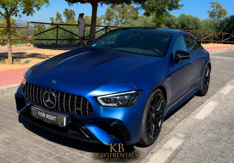 Matte blue Mercedes-AMG GT 63 S 4-Door Coupe luxury car rental parked on a sunny street in Marbella.