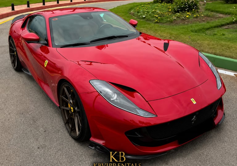 Red Ferrari 812 Superfast luxury sports car parked on a paved road in Marbella.