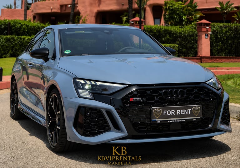 A light blue Audi RS3 luxury sedan for rent parked in front of a villa in Marbella, Spain.