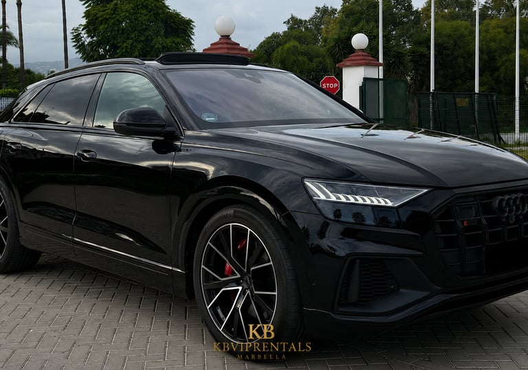 Black Audi Q8 luxury SUV rental parked on a stone driveway in Marbella.