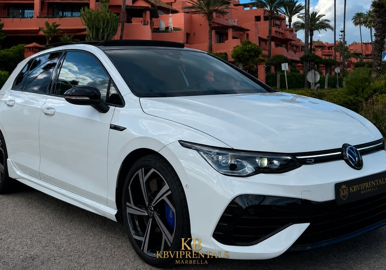 White Volkswagen Golf R luxury rental car parked in front of a Mediterranean resort in Marbella.