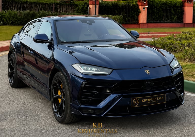 Luxury dark blue Lamborghini Urus SUV parked on a paved road for luxury car rental.