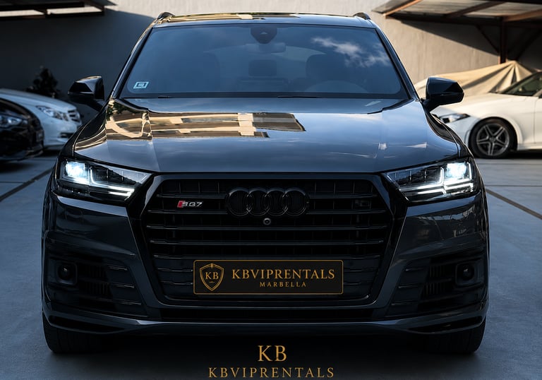 Front view of a black Audi SQ7 luxury SUV rental in Marbella with headlights on.