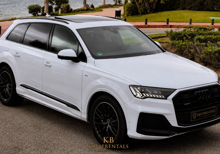 White Audi Q7 luxury SUV with black rims parked on a scenic coastal road in Marbella.