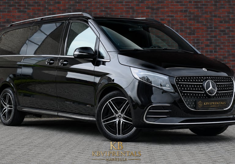 Luxury black Mercedes V-Class van parked in front of a brick wall for VIP chauffeur rental services.