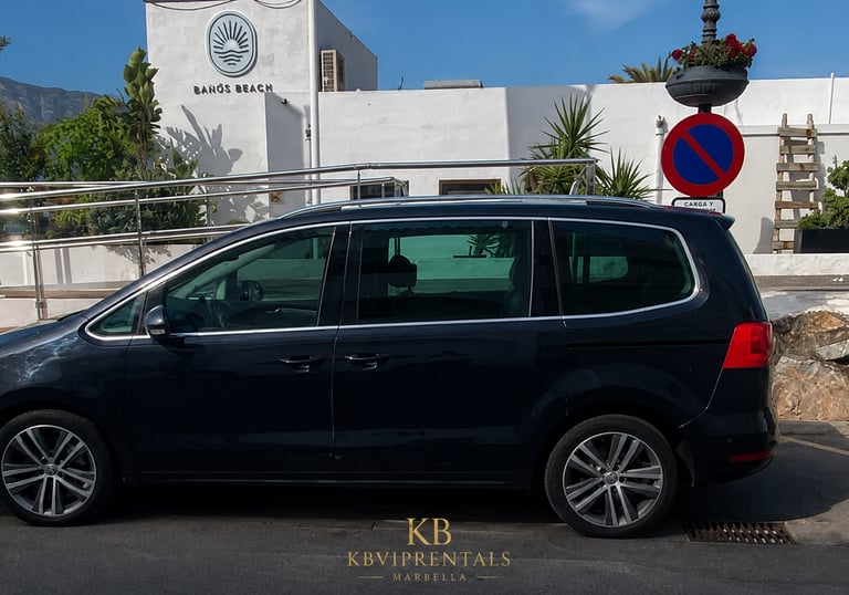 Black Volkswagen Sharan luxury minivan rental parked at Baños Beach club in Marbella.