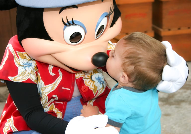 A toddler kisses Minnie Mouse's nose during a Disney vacation character meet and greet.