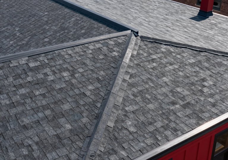 Top-down view of a completed high-durability residential roof in New York City with clean structural lines, dark gray shingles, and architectural red accents.