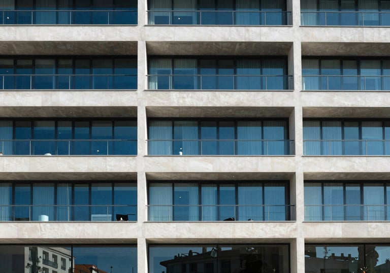Minimalist architectural detail of a modern Spanish office building with clean lines and blue glass windows under bright sunlight.