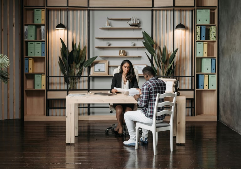 a man and woman sitting at a table with a laptop