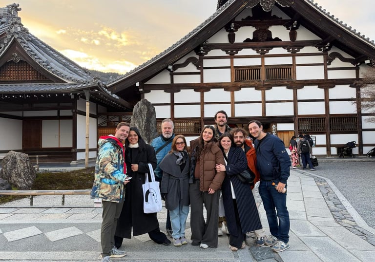 A group of friends posing in front of a traditional Japanese Buddhist temple in Kyoto during sunset.