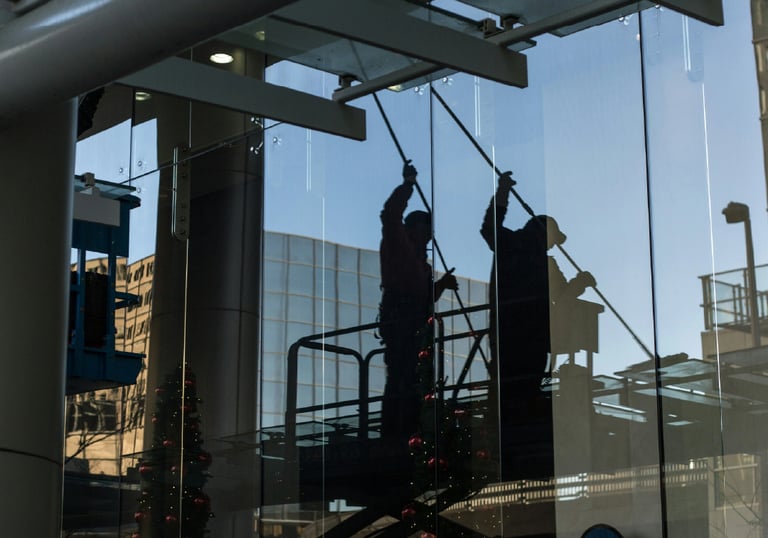 Persona limpiando un vidrio de un edificio.