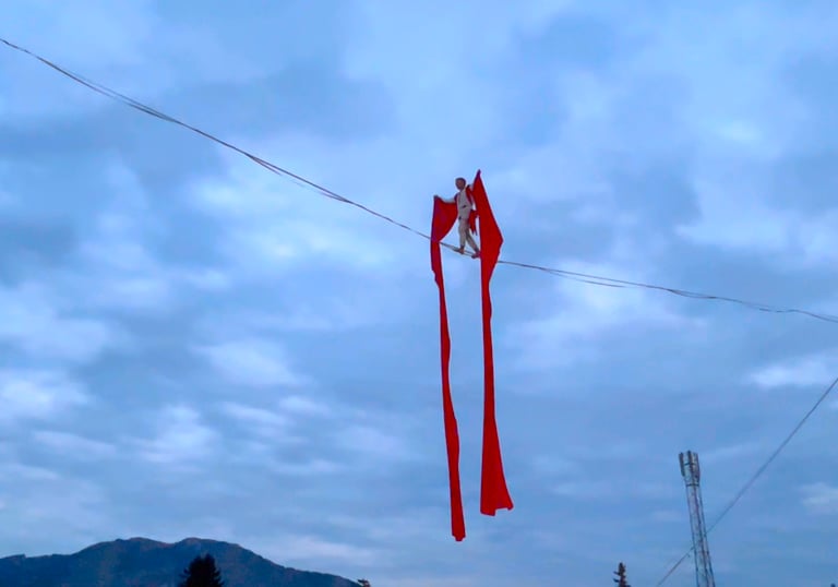 Moment poetique, un funambule traverse une ligne drapé dans un grand tissu rouge