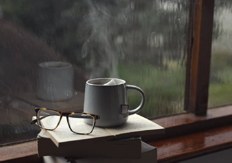 a cup of coffee and a book on a stack of books