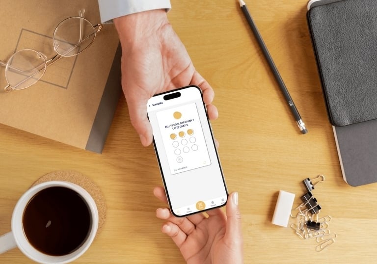 a person handing a phone with a digital loyalty card