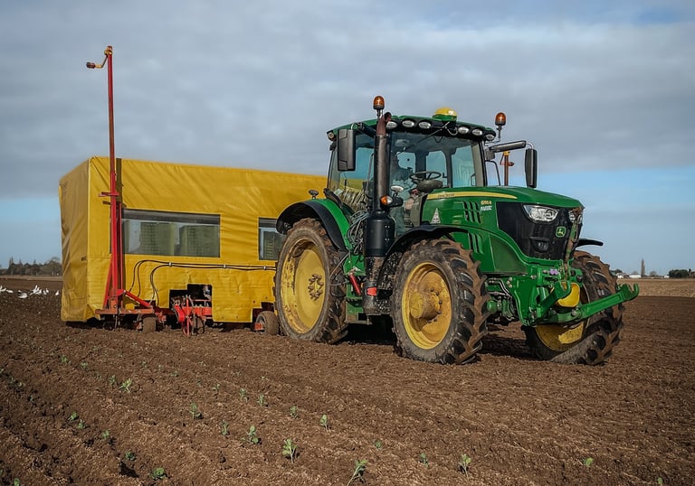 A tractor in a field with a planter behind