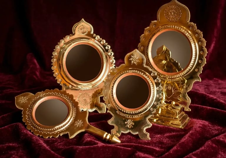Handcrafted Aranmula Kannadi metal mirrors with ornate gold brass frames on a red velvet background.