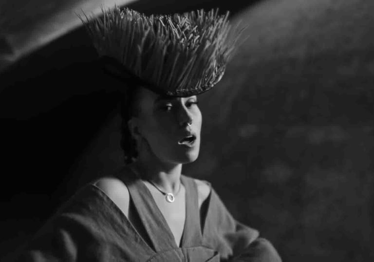 Juodai baltas merginos, dėvinčio avangardinę šiaudinę karūną, portretas dramatiškame apšvietime.