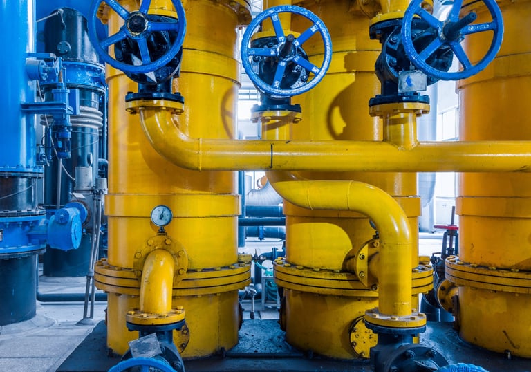 Tanques industriales de almacenamiento amarillos con válvulas de control azules y tuberías metálicas