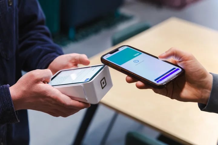 Customer using a smartphone for a contactless mobile payment at a Square card terminal.