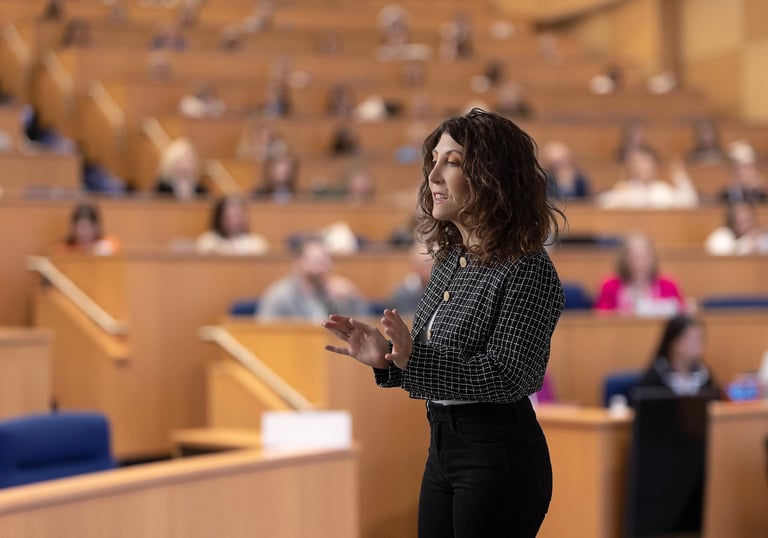 A woman in business attires speaks to an audience in a lecture hall.