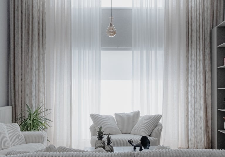 Modern living room with high ceilings, tall sheer curtains, and white corduroy sofas.