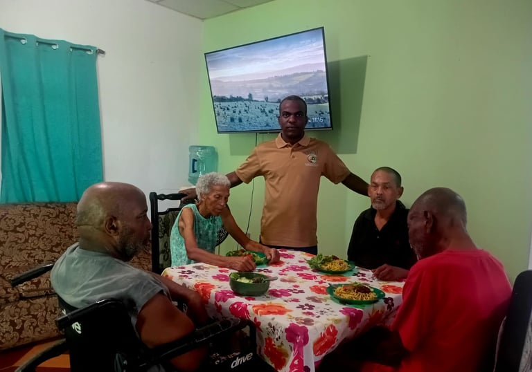 A group of senior citizens enjoying a meal together at a floral-covered table in a community care facility.