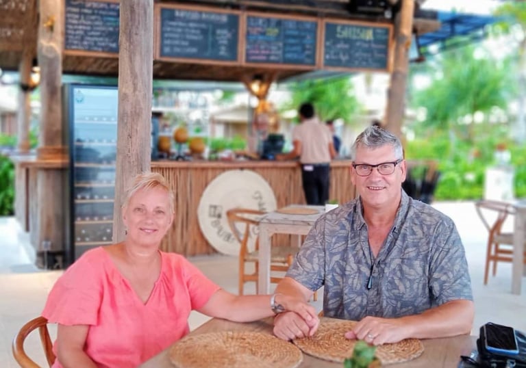Couple enjoying a relaxed, tropical dinner in a resort restaurant. Ideal for Bali Retirement Visa clients.