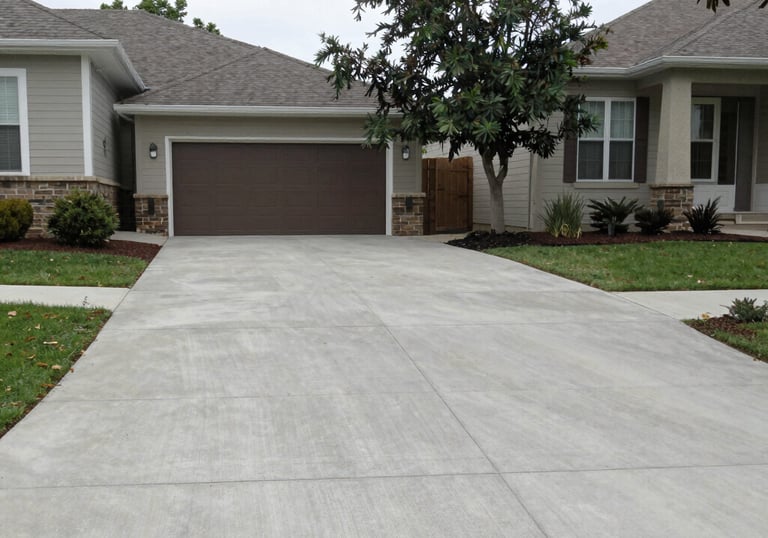 A freshly poured concrete driveway with clean lines and a smooth finish under a bright sky.