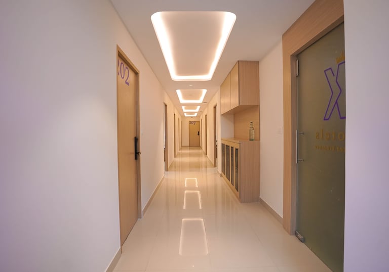 Modern hotel corridor featuring minimalist wood doors, bright white walls, and elegant recessed ceiling lighting.