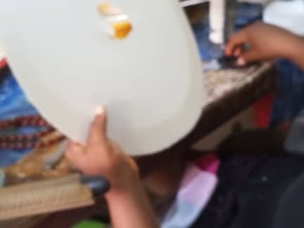 Close-up of a person holding a white circular craft template in a workshop setting.