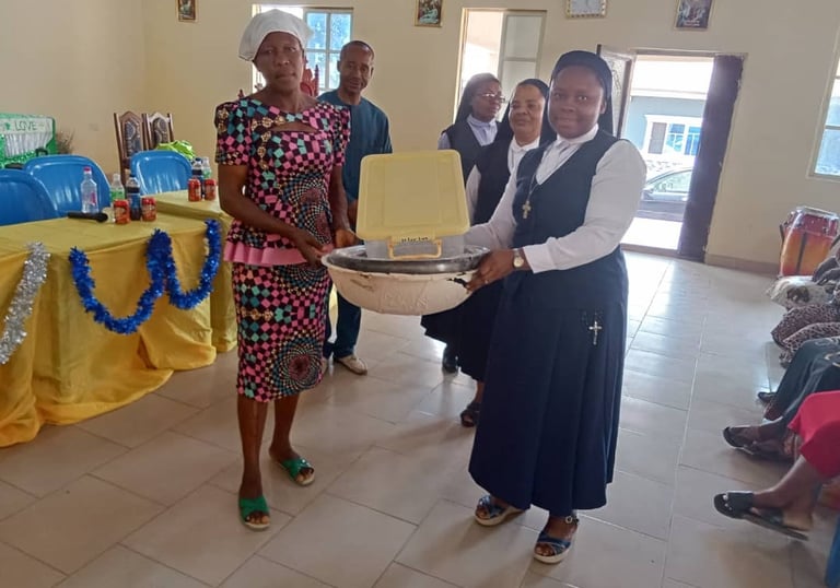 Catholic nuns presenting a donation basin to a woman in a colorful dress during a community outreach event.