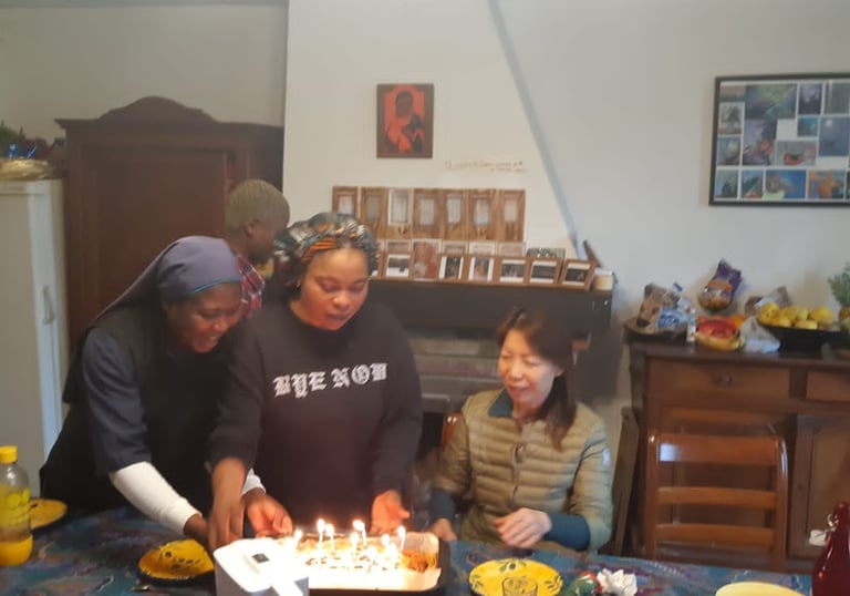 Friends celebrate a birthday together with a glowing candle-lit cake at a dinner party.