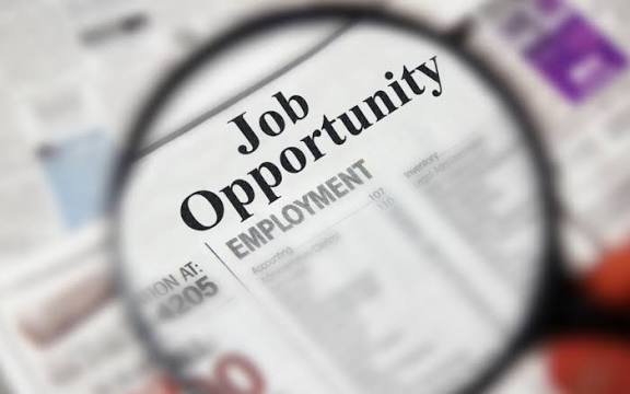 A magnifying glass focusing on a job opportunity and employment listing in a newspaper.