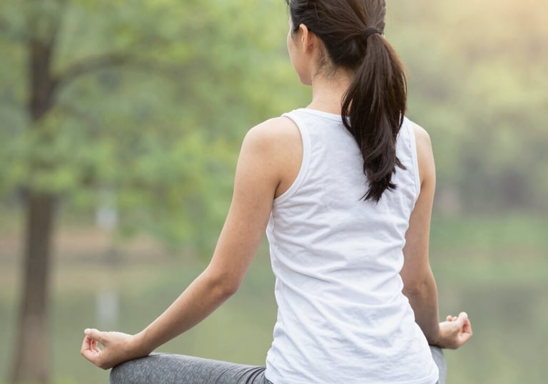 A serene woman practicing breathing exercises in a softly lit room with green and terracotta accents.